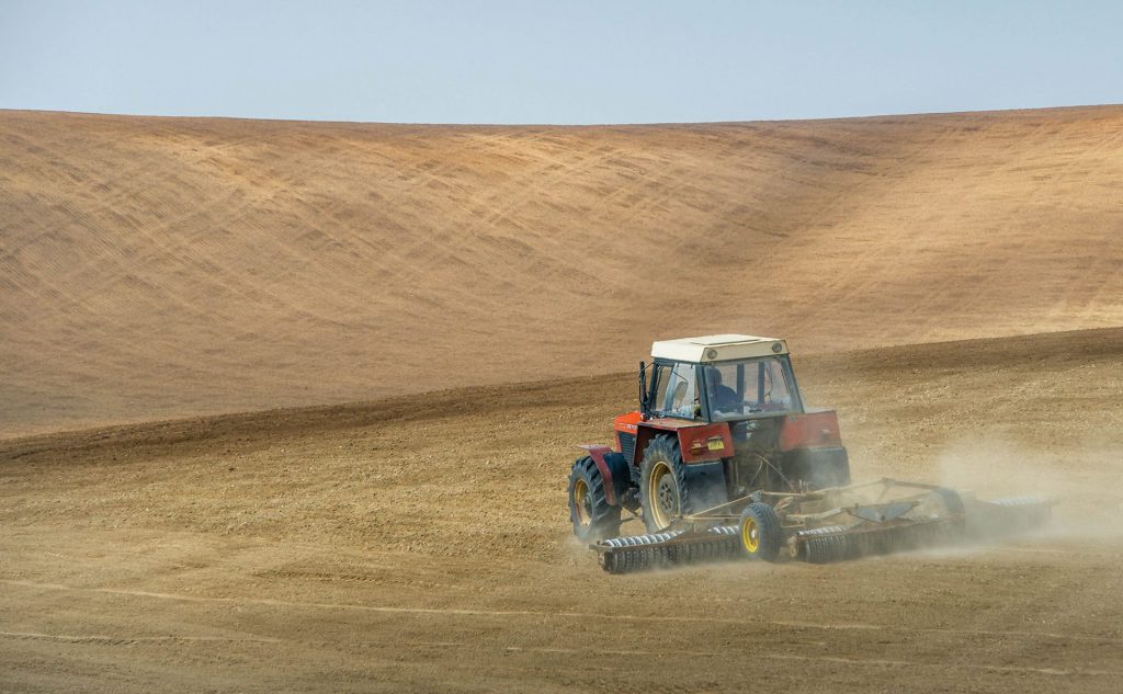 Landscape photo of a farmer working on his hilly fields in Moravia