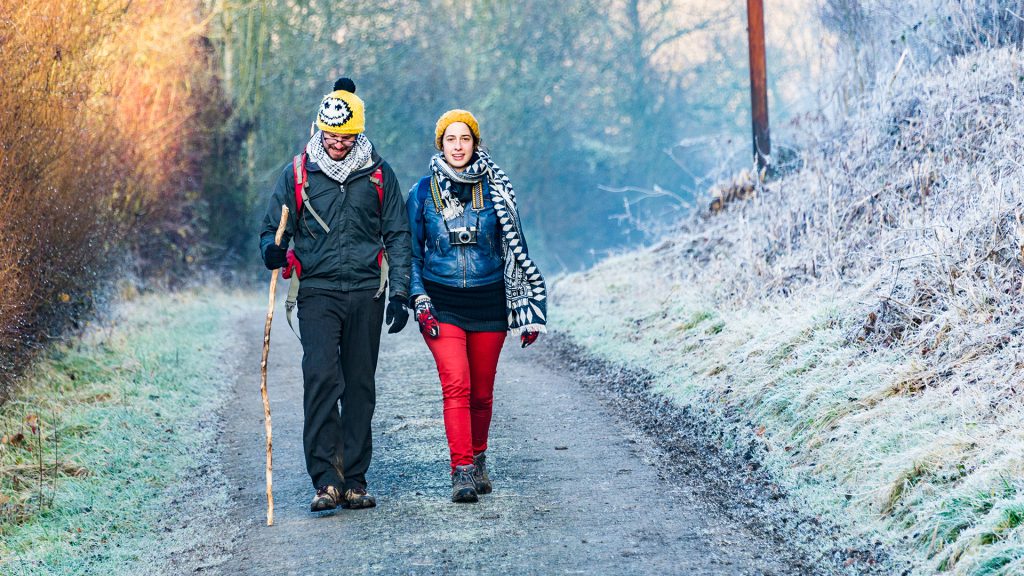 colorful winter landscape photo of young couple walking side by side warmly dressed