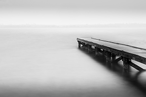 minimal black and white lang exposure photo of a jetty