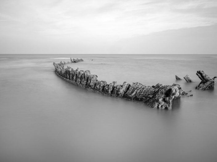 black and white landscape long exposure of a shipwreck at the Opal coast North of France