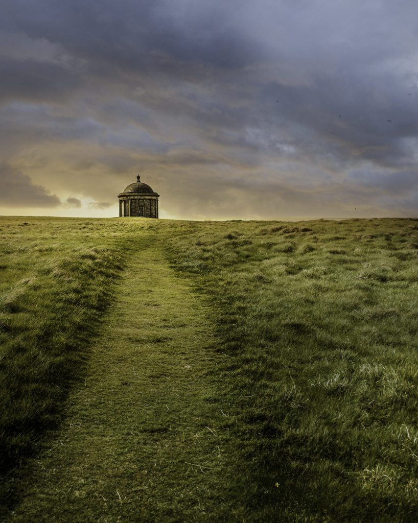 Minimal landscape photo of a well-trodden grass path leading to the focal point