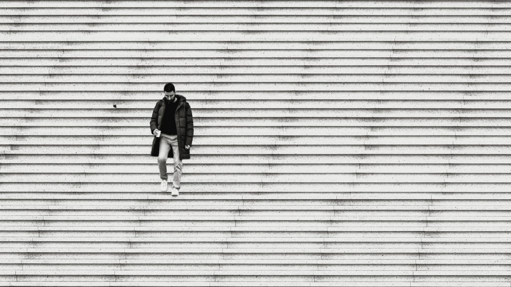 Minimal black-and-white cityscape of a man walking down enormous stairs