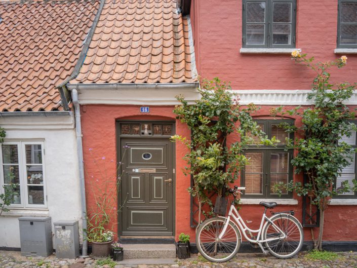 Cityscape photo of a bike in front of a red cottage in Ribe, Denmark