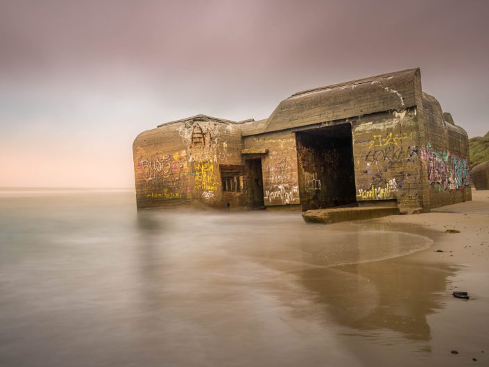 long exposure landscape photo of a bunker sinking into the sea because of erosion along the cost in Denmark