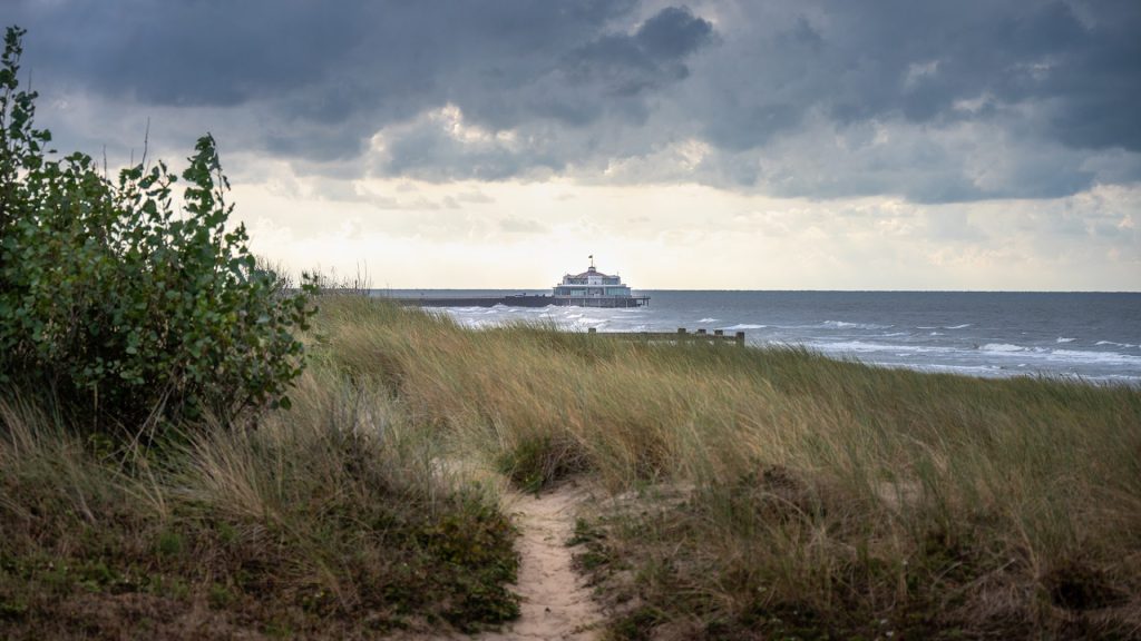 seascape photo of the Pier in Blankenberge, Belgium, with grass and a sand path in the foreground