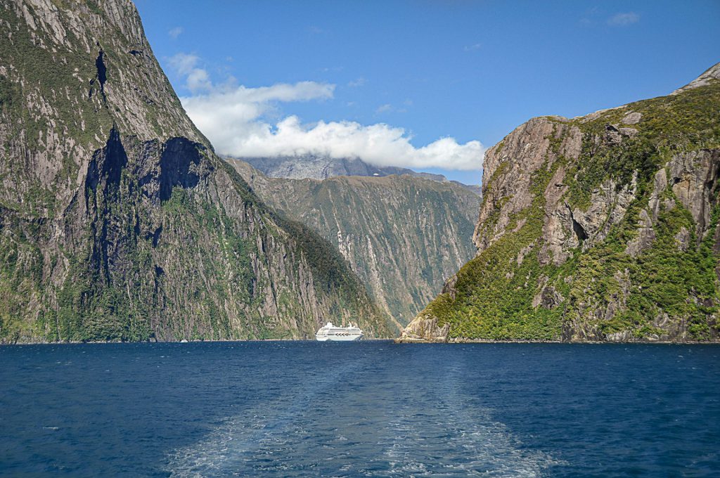 seascape with leading lines caused by a boat toward cruise ship and rocks