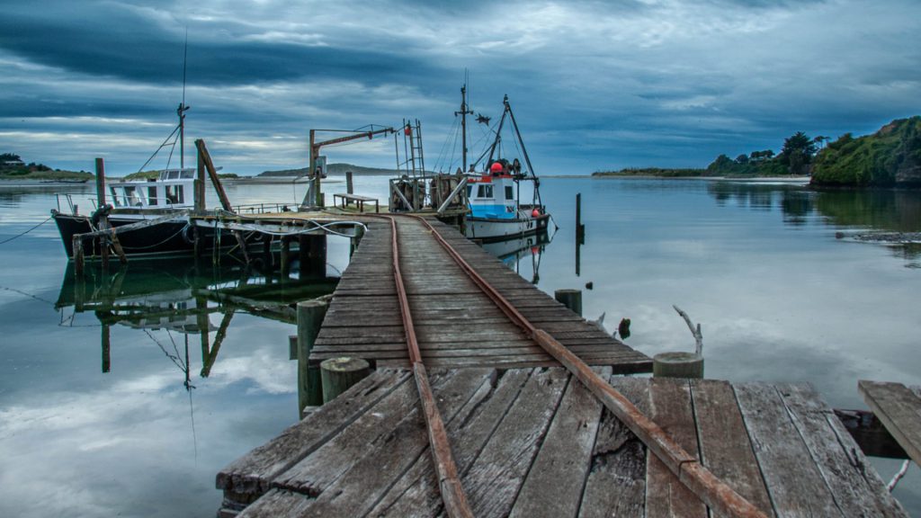 Blue hour fishing boat seascape photo with leading lines of tracks toward the boats