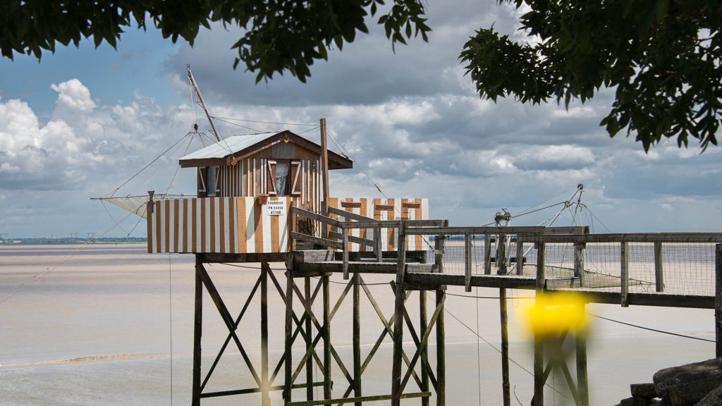 Seascape photo of fishing hut with branches framing the view