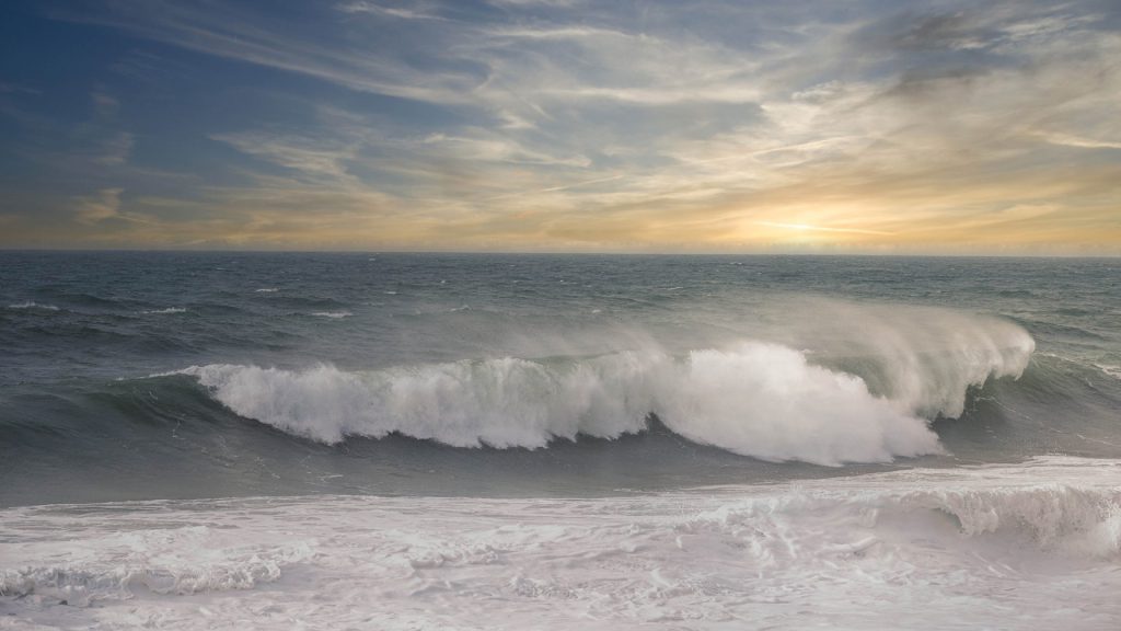 seascape photo of a large wave in the evening sun