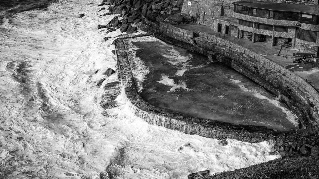 black and white seascape photo with waves going in and out a swimming pool at high tide