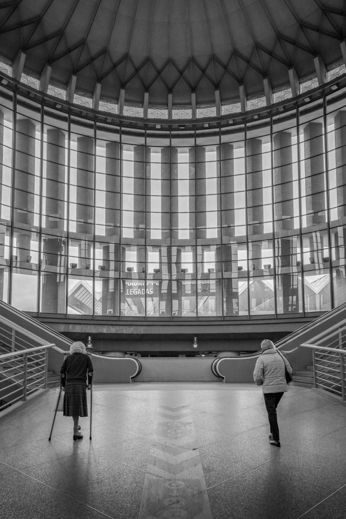 Street photo in black and white of people walking in the entrance hall of the central railway station in Madrid.