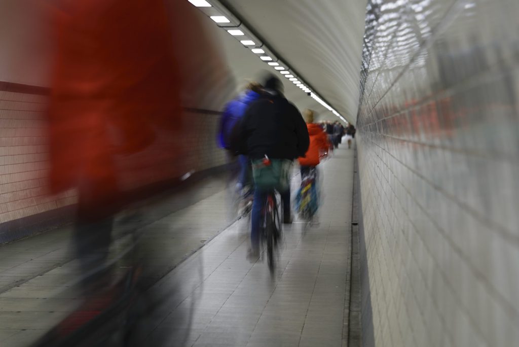 cityscape photo of bikers in a tunnel with long exposure blur