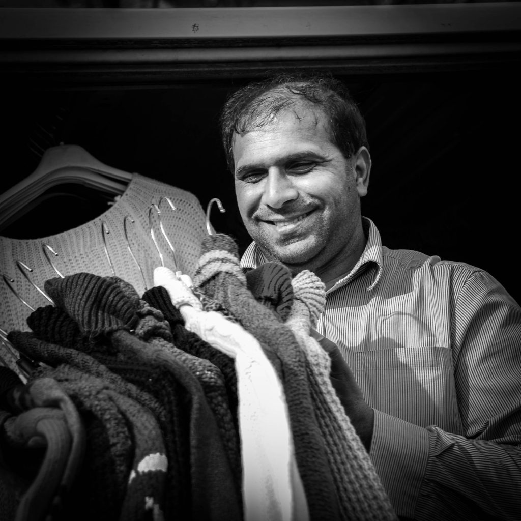 Street photo in black and white of a clothes salesman on the market in Ghent, Belgium
