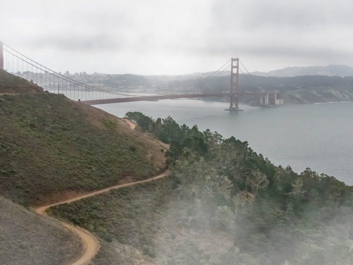 Landscape photo of the Golden Gate Bridge in the mist with a dirt road as the leading line.